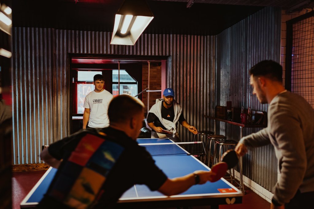 A group of guys playing ping pong at Roxy.