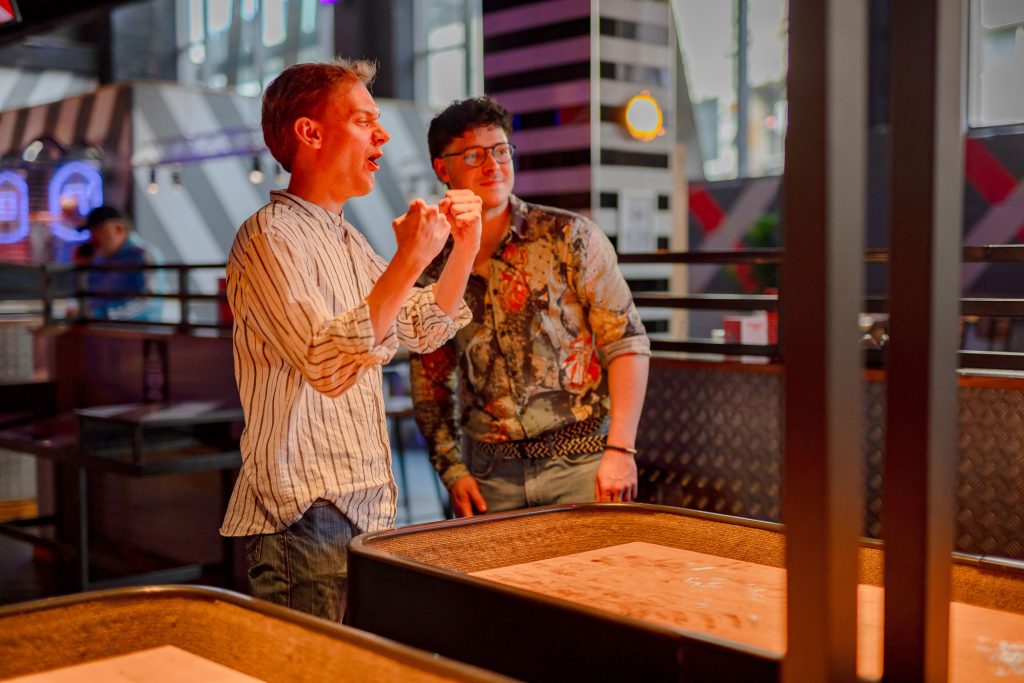 A man celebrating a win at Shuffleboard at Roxy.